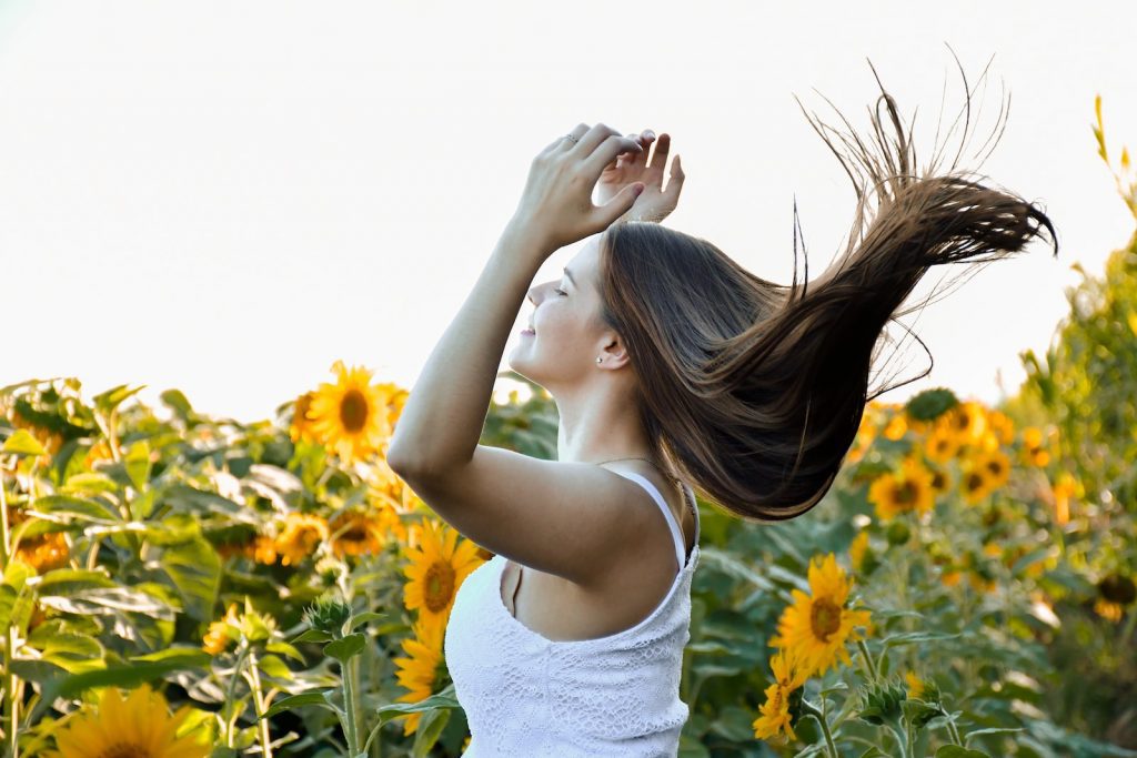 woman in white tank top standing on yellow flower field during daytime